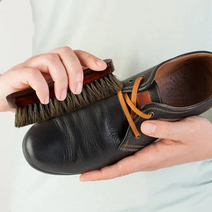 Hand using a bristle brush on a shoe