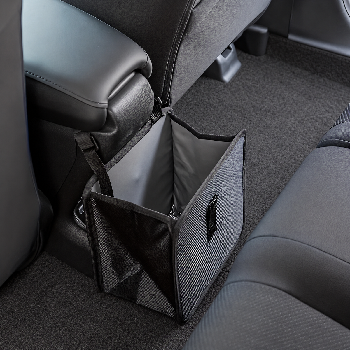 Open black hanging car bag beside a center console showing its gray lining and side mesh